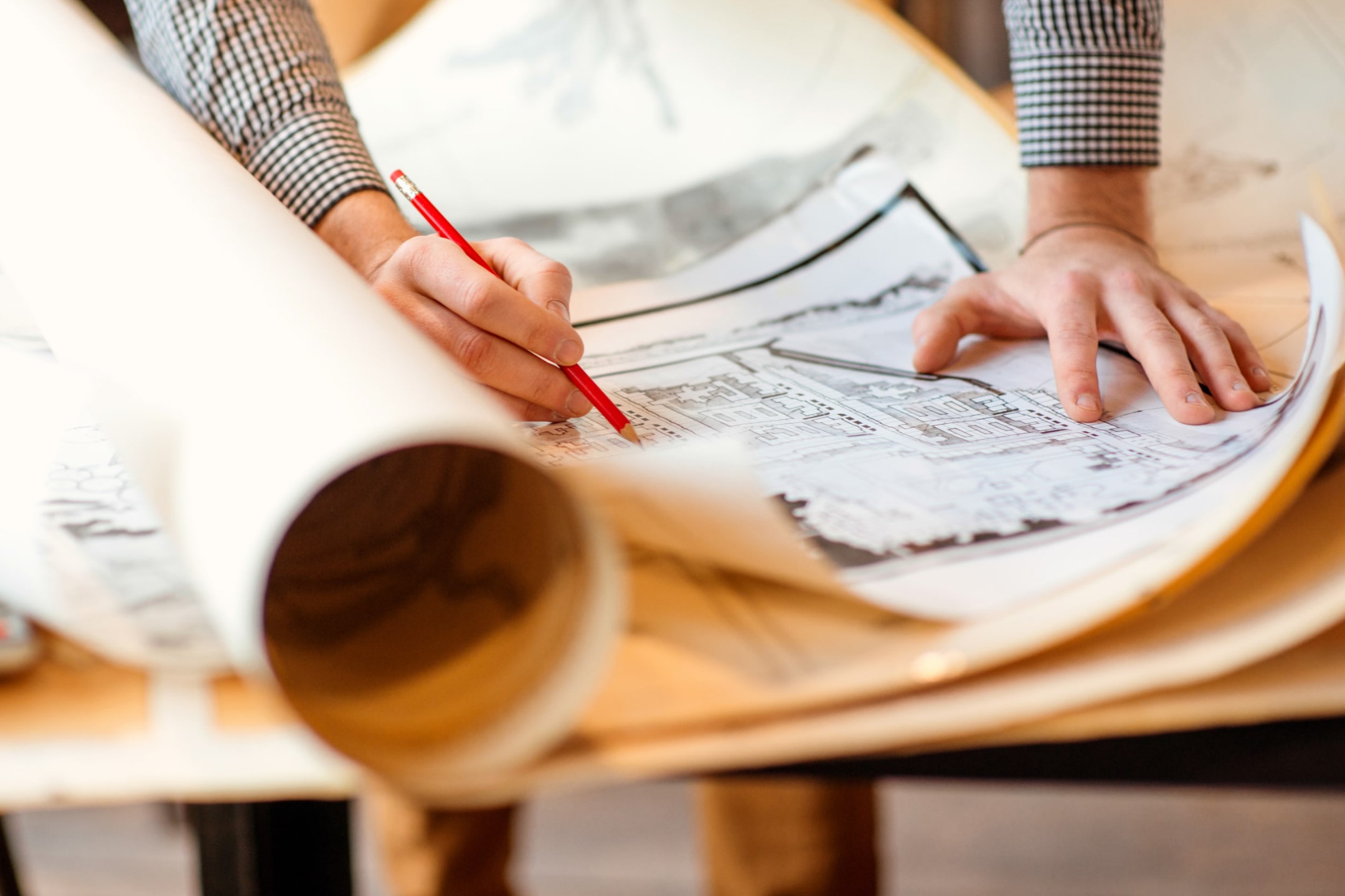 Picture of guy drawing on set of building plans.